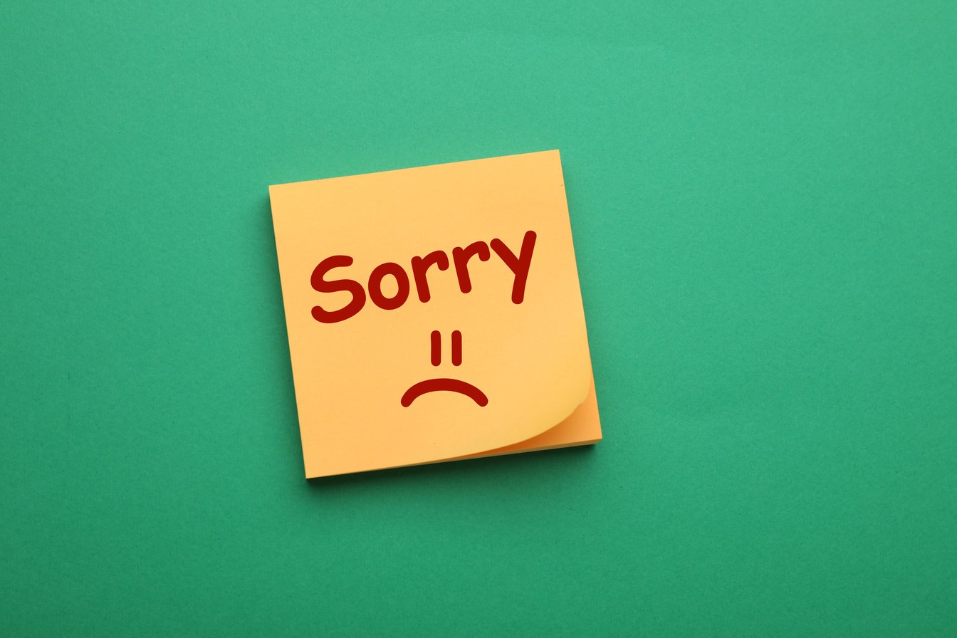 Apology. Sticky Note with Word Sorry and Drawn Sad Face on Green Background, Top View