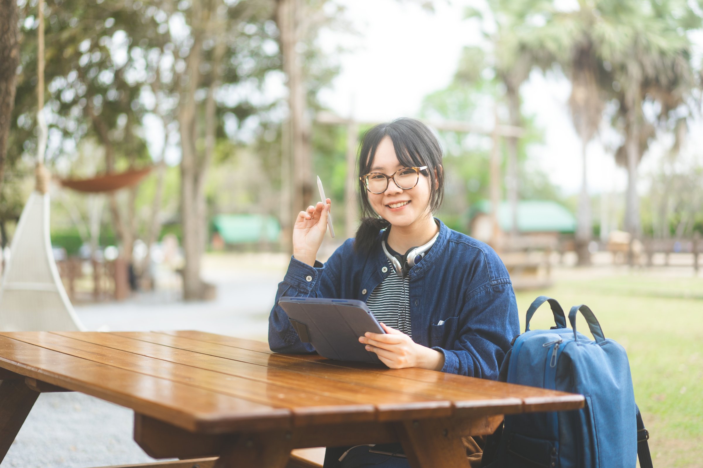 Young adult asian woman using digital tablet for digital nomad work and study